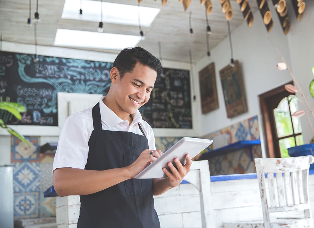 Business Insurance - Closeup Portrait of a Smiling Young Hispanic Cafe Owner Using a Tablet