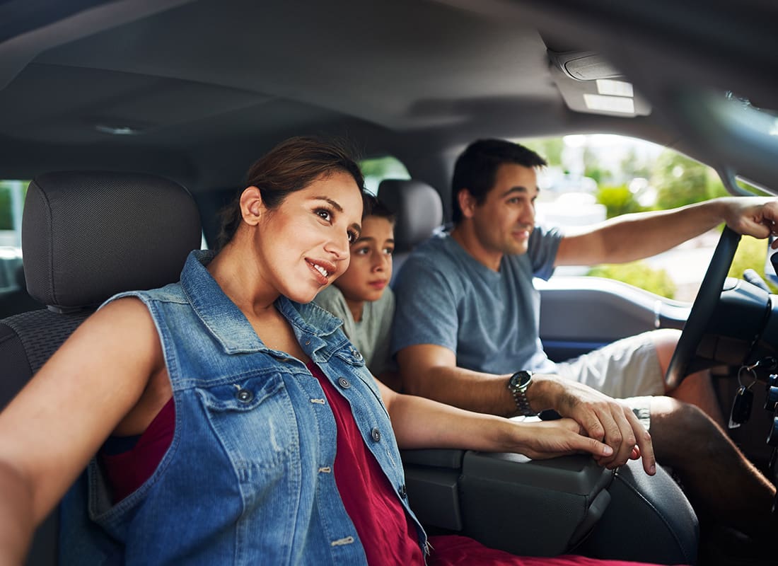 Insurance Solutions - Portrait of a Family with a Young Son Sitting in a Car During a Summer Road Trip