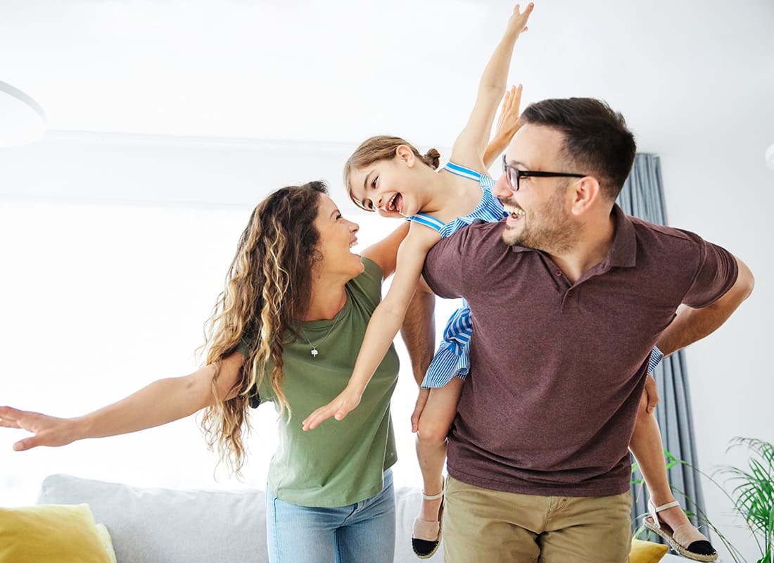 Personal Insurance - Portrait of an Excited Mother and Daughter Having Fun Playing with Their Young Daughter in the Living Room